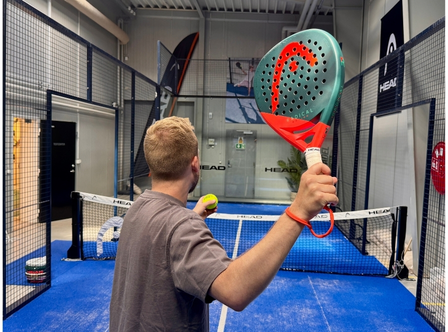 Mies pitelee vihreää ja punaista HEAD Radical -padelmailaa sekä palloa – testi keskitason pelaajille