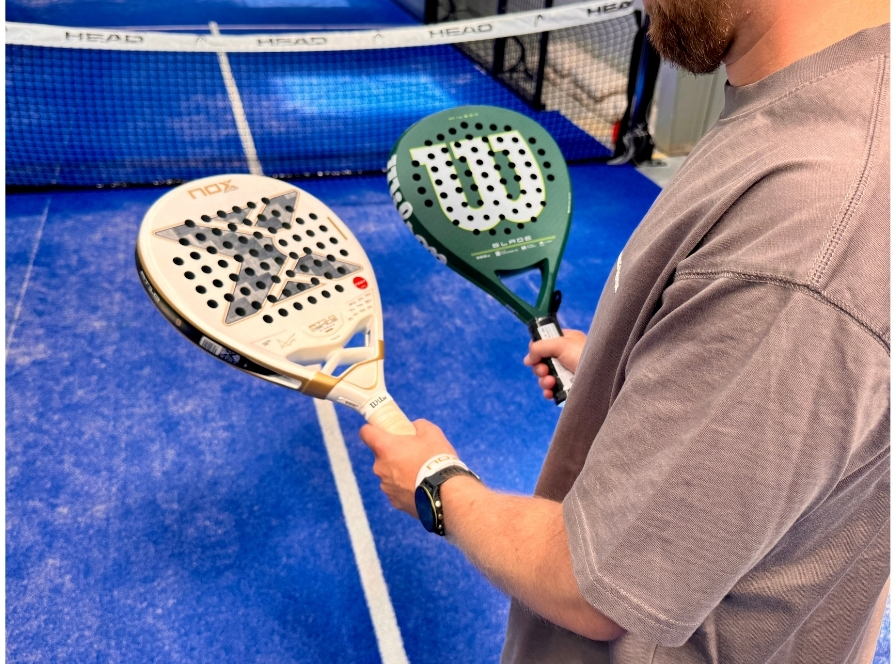 Padel-pelaaja pitelee mailaa ja palloa valmiina testaamaan kokeneiden pelaajien varusteita